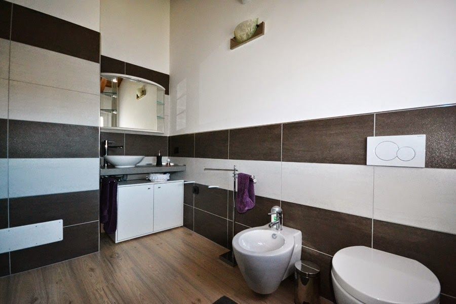 Piccolo bagno moderno con piastrelle bianche e nere, lavabo, mobiletto con specchio, bidet e WC a vista.