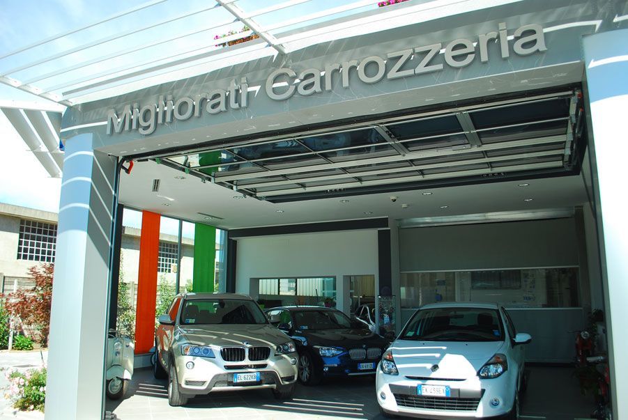 Showroom di una concessionaria automobilistica con tre auto parcheggiate all'interno, tra cui una BMW argentata all'ingresso.
