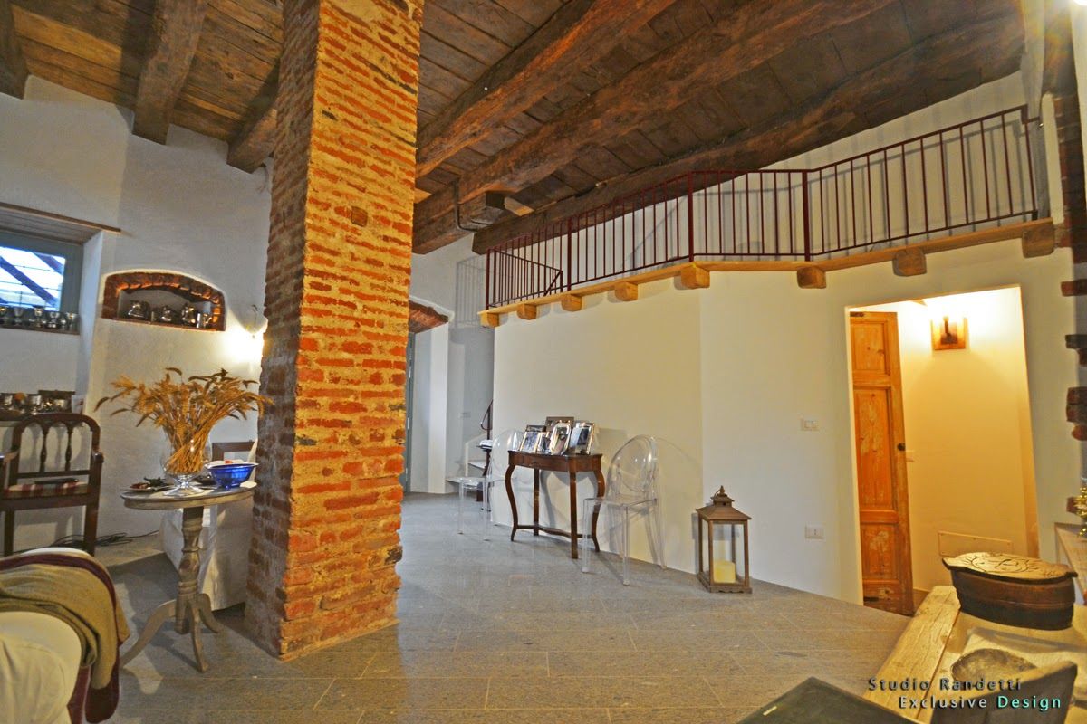 Interno rustico con pilastro in mattoni a vista, travi in ​​legno, pavimento in pietra e piccole lanterne in un corridoio luminoso.