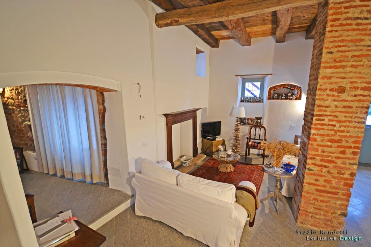 Camera da letto rustica con parete in mattoni a vista, travi in ​​legno, divano letto bianco e porta con tenda.
