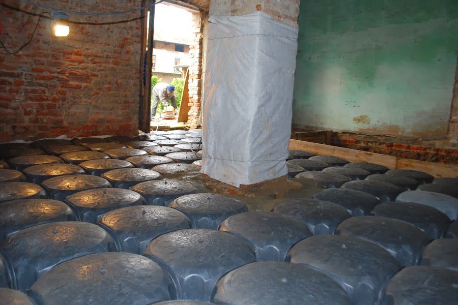 Interno con pavimento nero irregolare, pareti in mattoni e una colonna rivestita di bianco vicino a una porta.