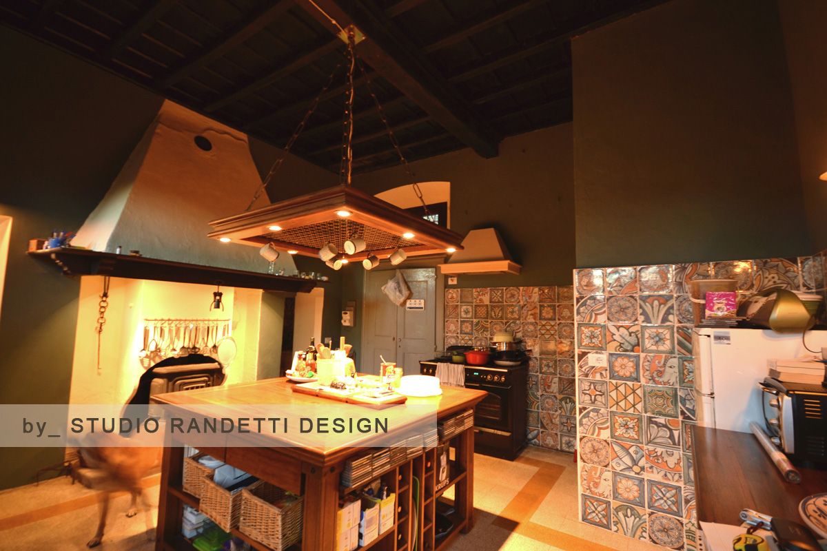 Accogliente interno rustico del ristorante con tavoli in legno, cappa aspirante, parete piastrellata e cucina a vista.