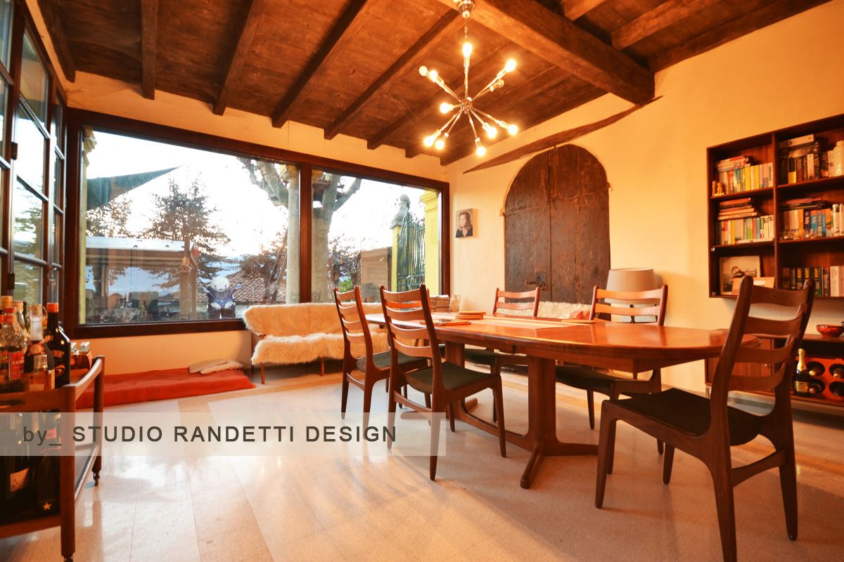 Accogliente sala da pranzo con tavolo e sedie in legno, soffitto a volta, camino e ampia panca vicino alla finestra per ammirare il tramonto.