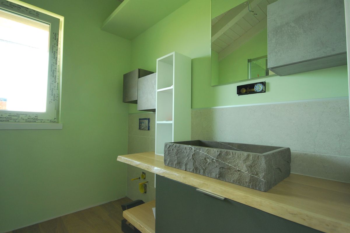 Stanza verde con finestra, scaffalature a muro e un piano d'appoggio con un blocco di pietra.