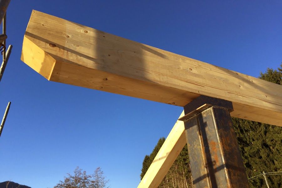 Struttura in travi di legno in costruzione sullo sfondo di un cielo azzurro.