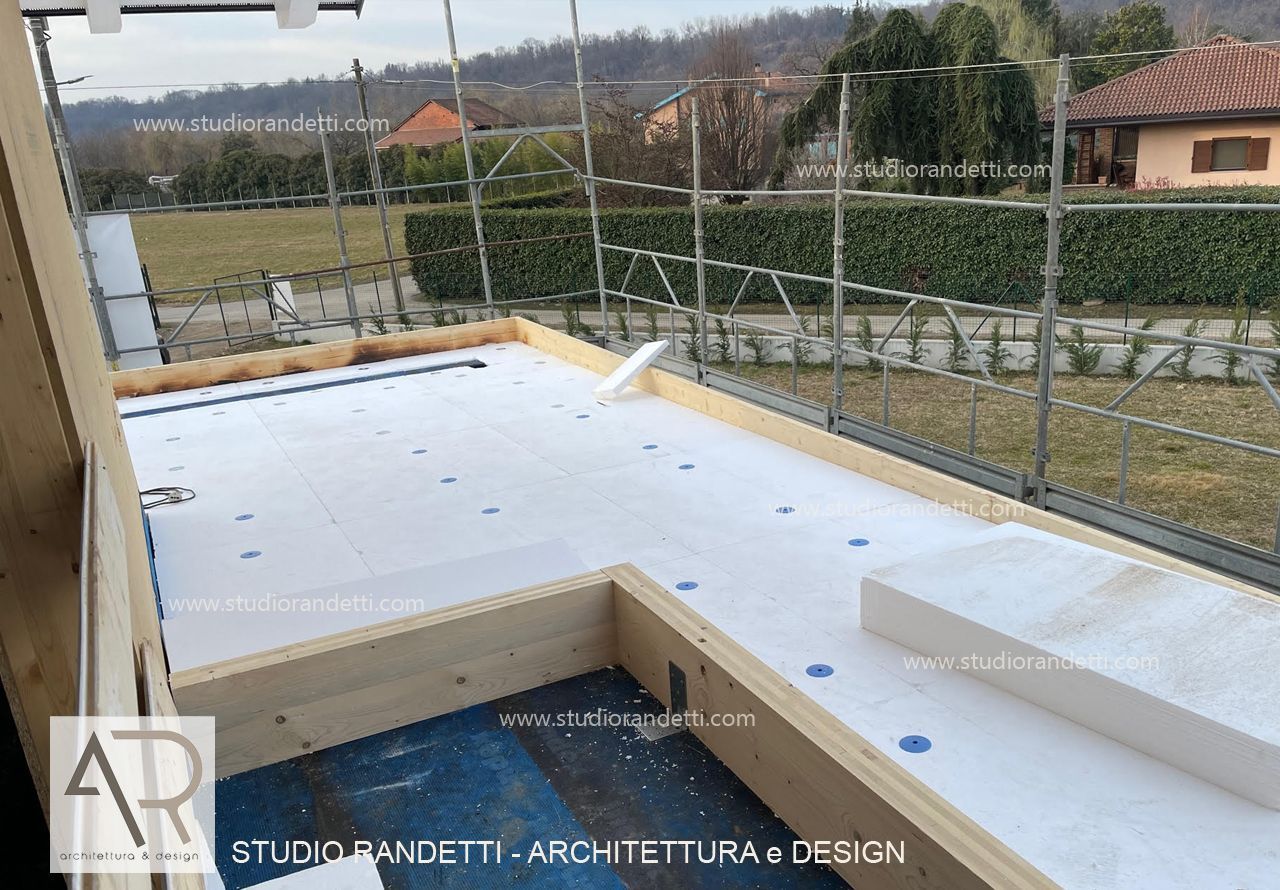 Terrazza sul tetto bianca impermeabilizzata in costruzione accanto a un cortile recintato e a delle case, giornata nuvolosa