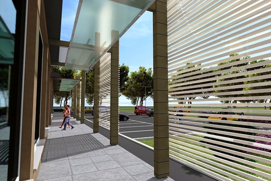 Passerella di un edificio moderno con tettoia in vetro, schermi a strisce e una persona che cammina tra le auto parcheggiate.