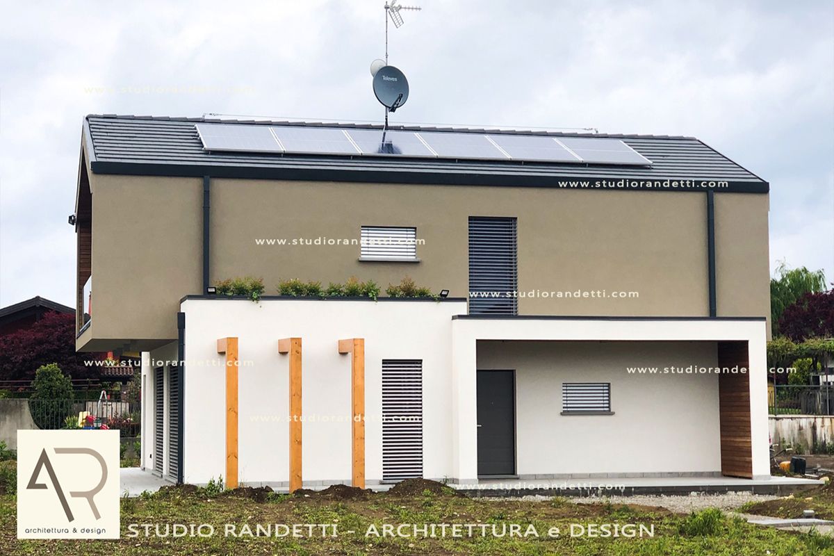 Casa moderna a due piani di colore beige con dettagli bianchi e tetto spiovente, mostrata frontalmente.