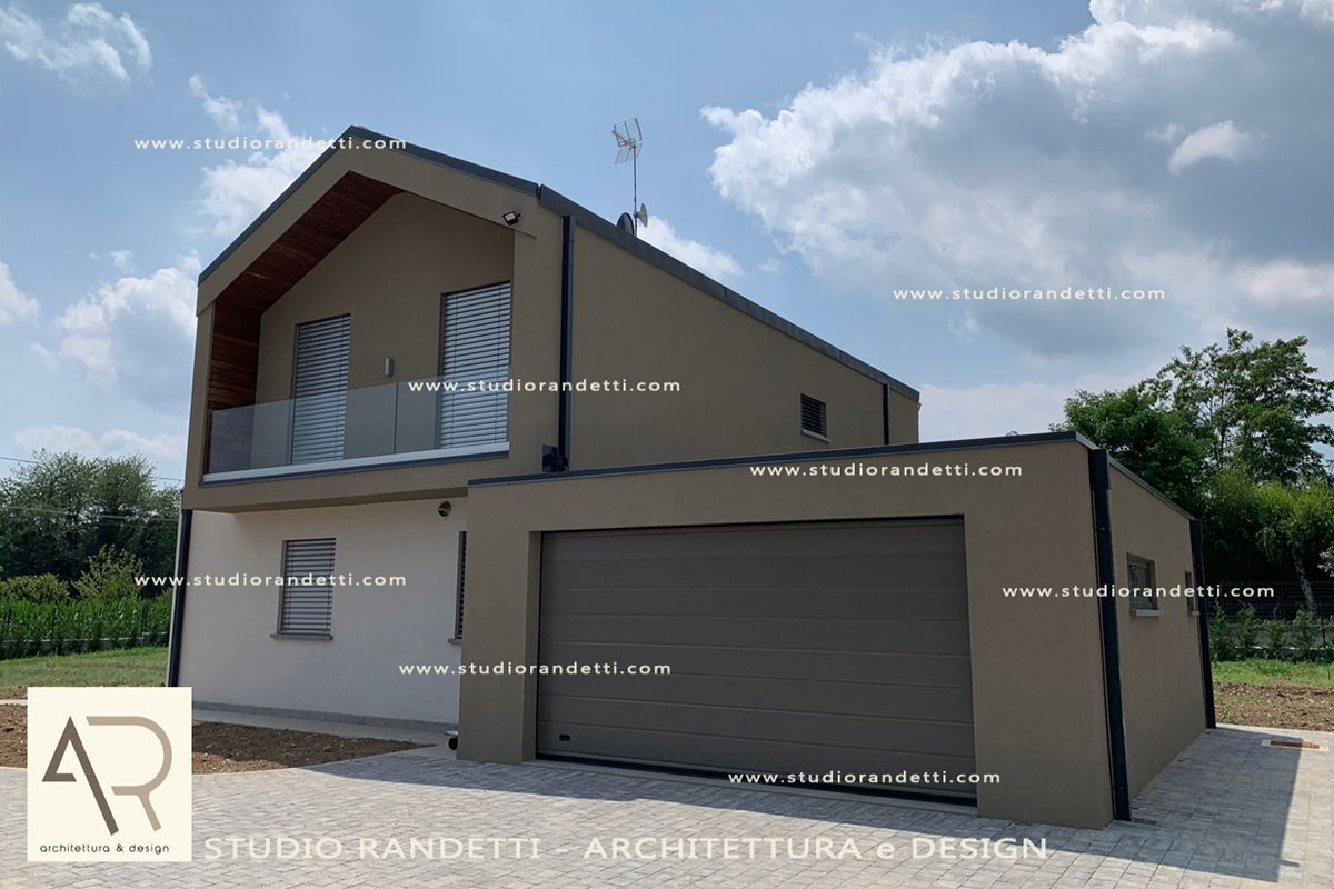 Casa moderna a due piani color beige con garage doppio e tetto spiovente in una giornata di sole.