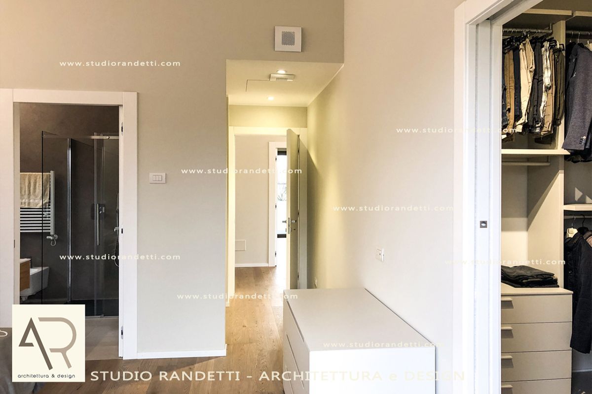 Luminoso corridoio con camera da letto, armadio a vista, pareti bianche e panca contenitore in una casa moderna