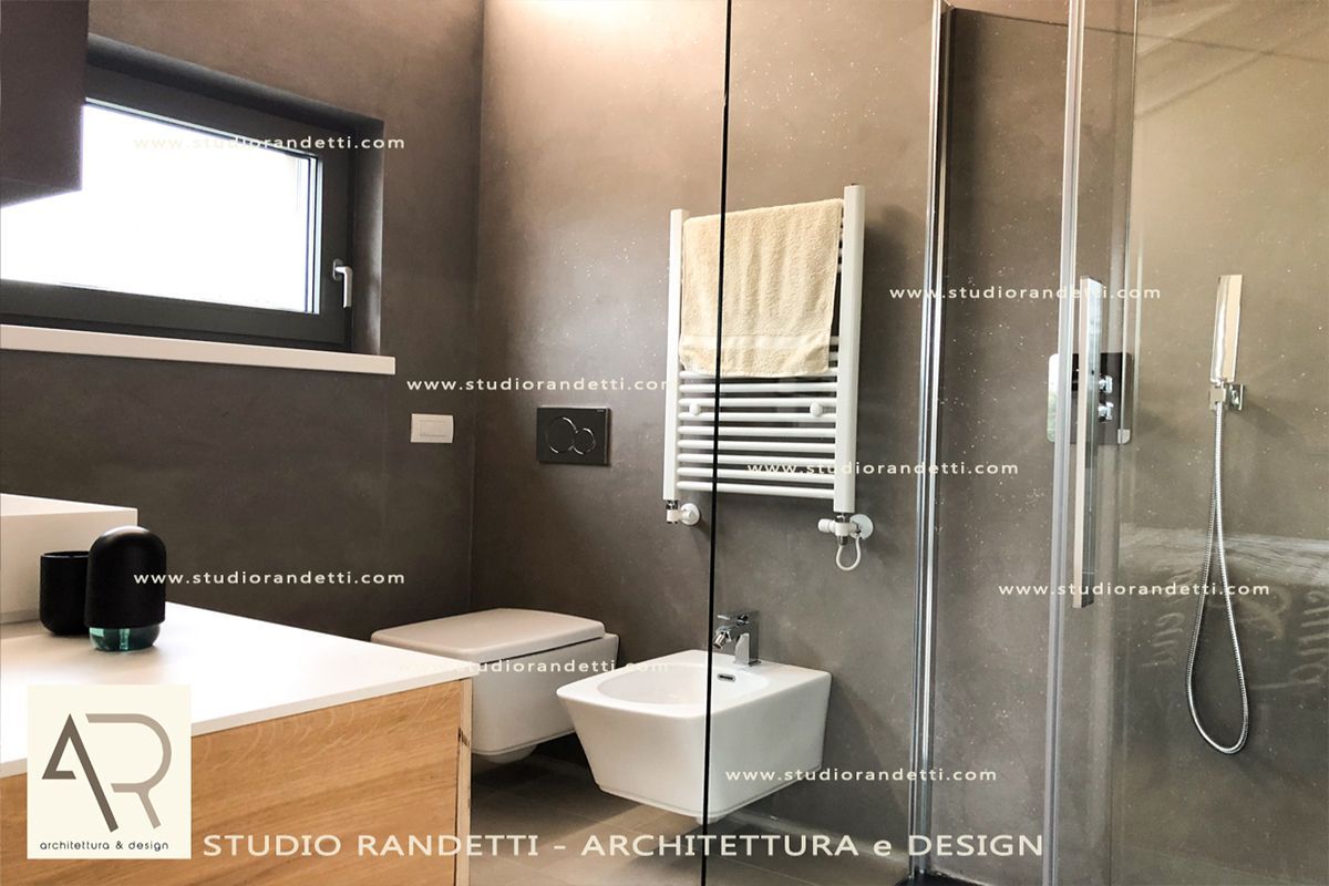 Bagno moderno con vasca da bagno, lavabo a parete, scaletta portasciugamani e cabina doccia nei toni del beige.