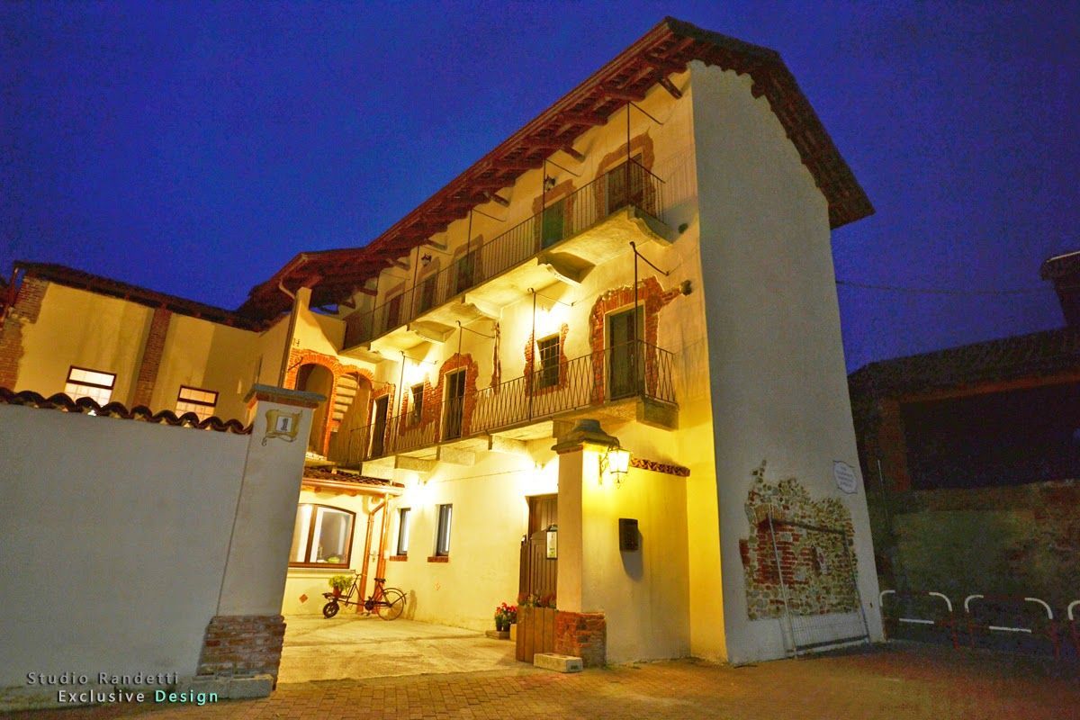 Cortile illuminato di un rustico edificio a due piani al crepuscolo, con calde luci gialle e balconi in legno.