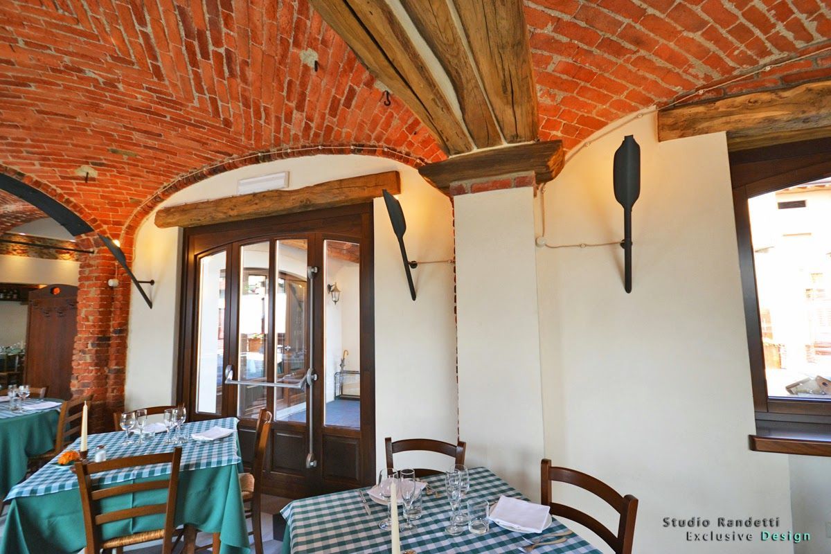 Caffè all'aperto sotto archi di mattoni con tovaglie a quadri e porte a vetri.