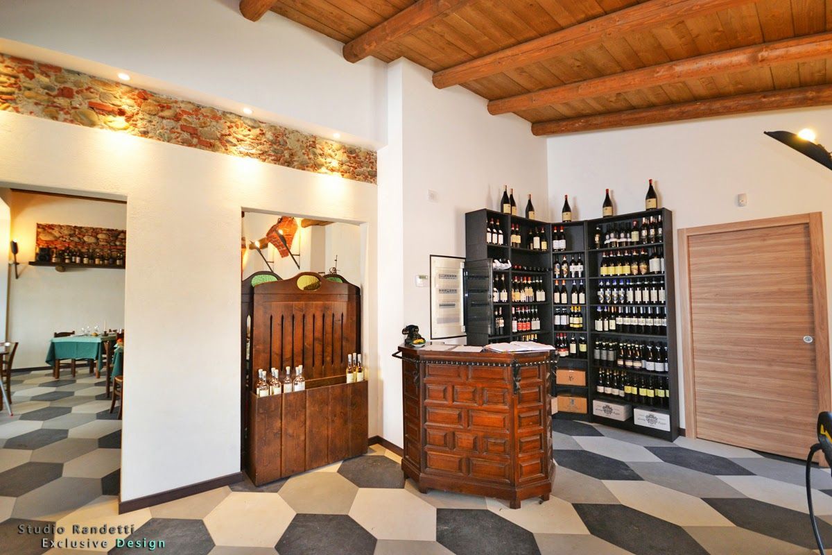 Interno di un'enoteca con soffitto in legno, pavimento piastrellato, scaffali di bottiglie e bancone espositivo.
