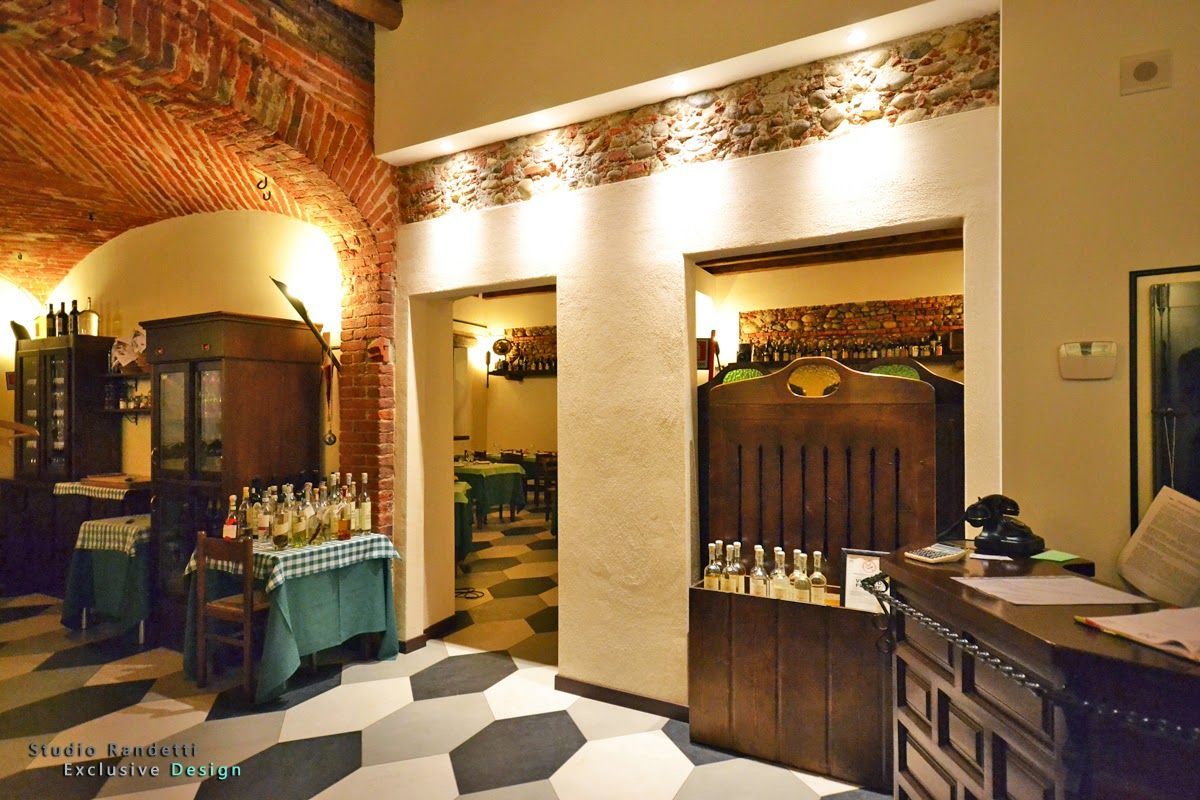 Interno accogliente di un ristorante o di una caffetteria con archi in mattoni, bancone in legno e pavimento piastrellato in bianco e nero.