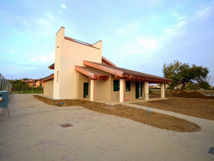 Casa a un solo piano in stucco con tetto di tegole rosse su un lotto sabbioso al tramonto