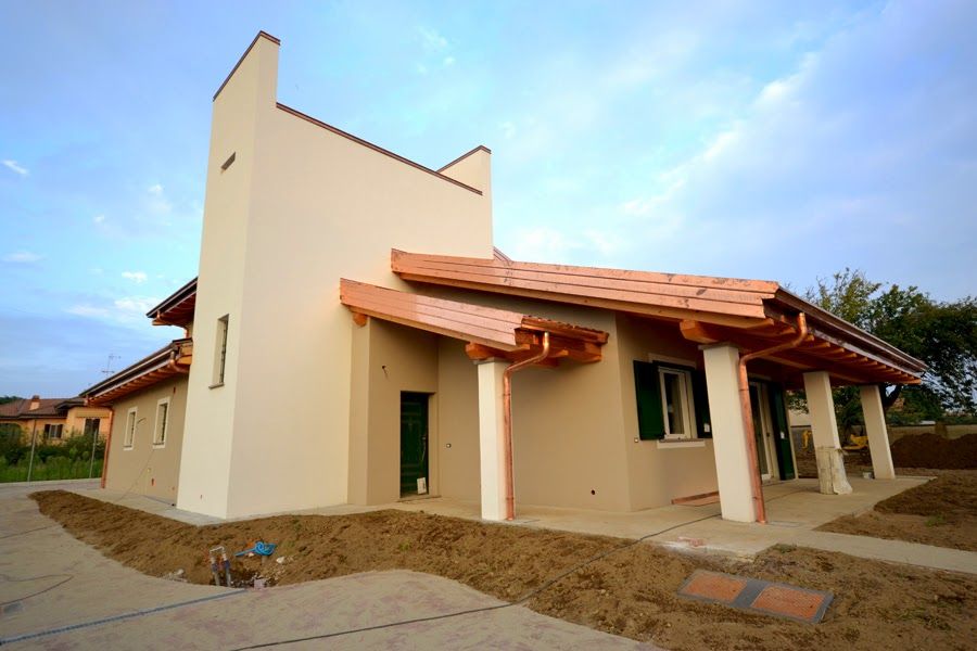 Piccola casa beige con tetto di tegole rosse e alta torre bianca, vista frontalmente.
