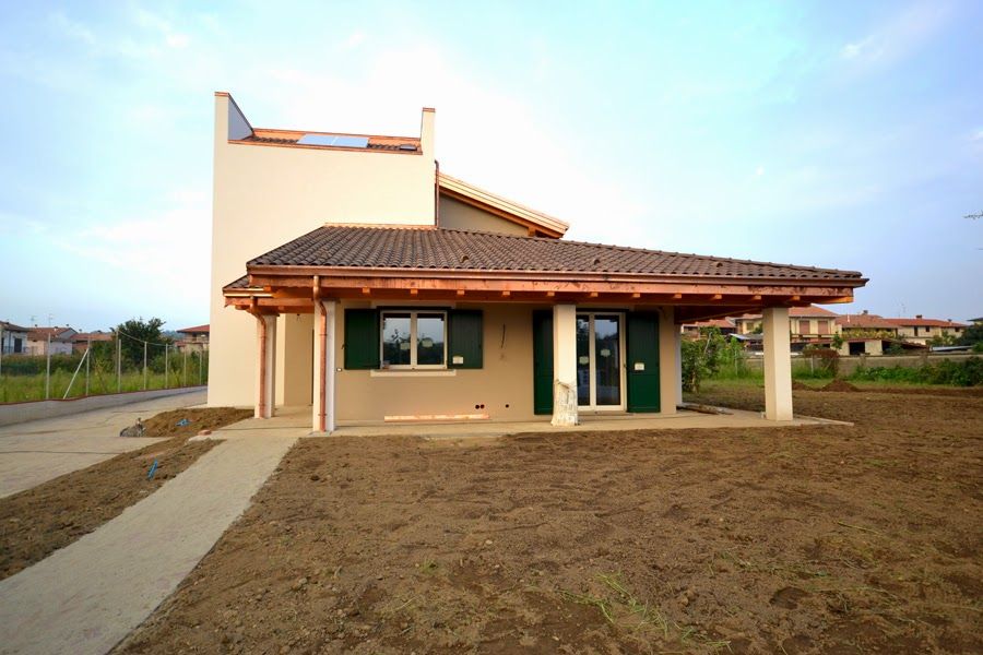 Casa moderna color beige con tetto di tegole e portico anteriore in un lotto erboso in periferia al tramonto