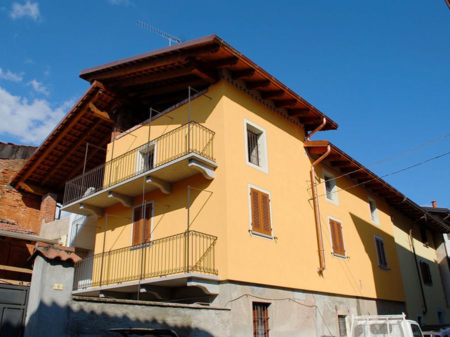 Casa in stucco giallo con balconi e tetto marrone sotto un cielo azzurro