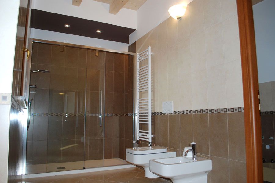 Bagno moderno con cabina doccia in vetro, bidet bianco e termoarredo.