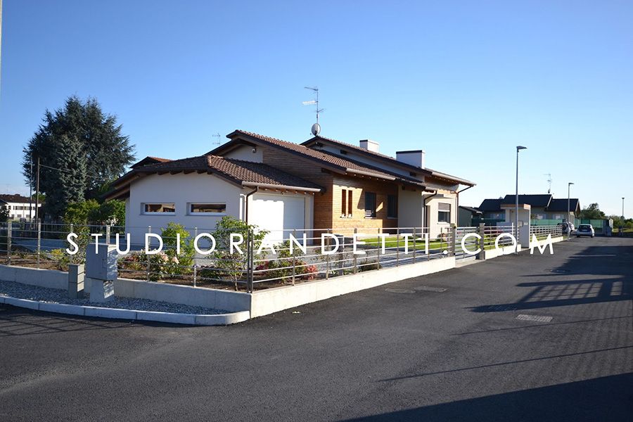 Casa a un solo piano con muro bianco e vialetto d'accesso, situata in un angolo di strada soleggiato.