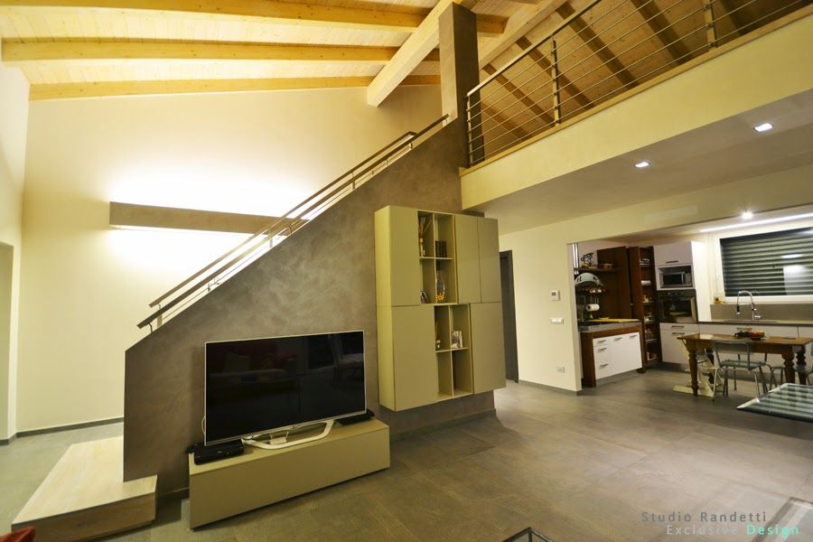 Soggiorno moderno con TV, scala, soffitto a volta e zona cucina/pranzo a vista.