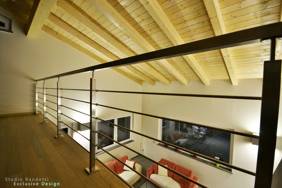 Soppalco con soffitto a volta in legno, ringhiere nere e vista sulla zona giorno inferiore.