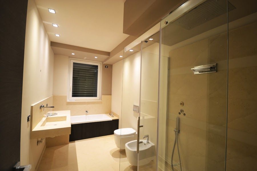 Bagno moderno color beige con lavabo, WC, vasca da bagno, doccia e illuminazione a incasso.