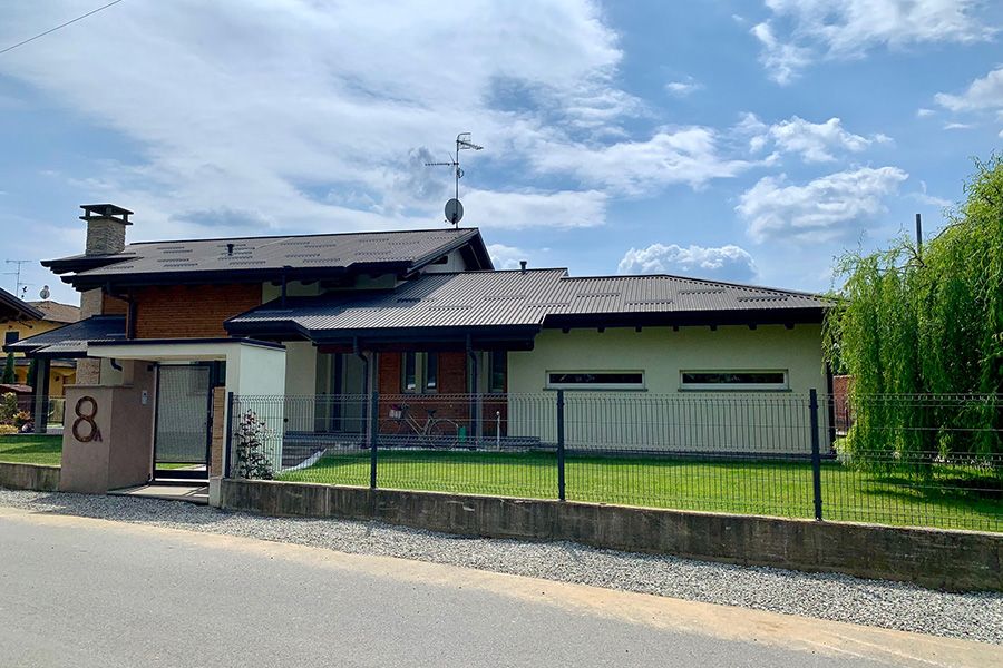 Casa a un solo piano con cortile anteriore recintato sotto un cielo azzurro brillante