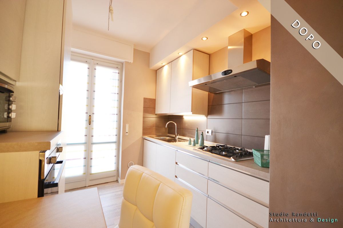 Cucina moderna e luminosa con mobili bianchi, pareti beige e una porta a vetri che si apre su un balcone.
