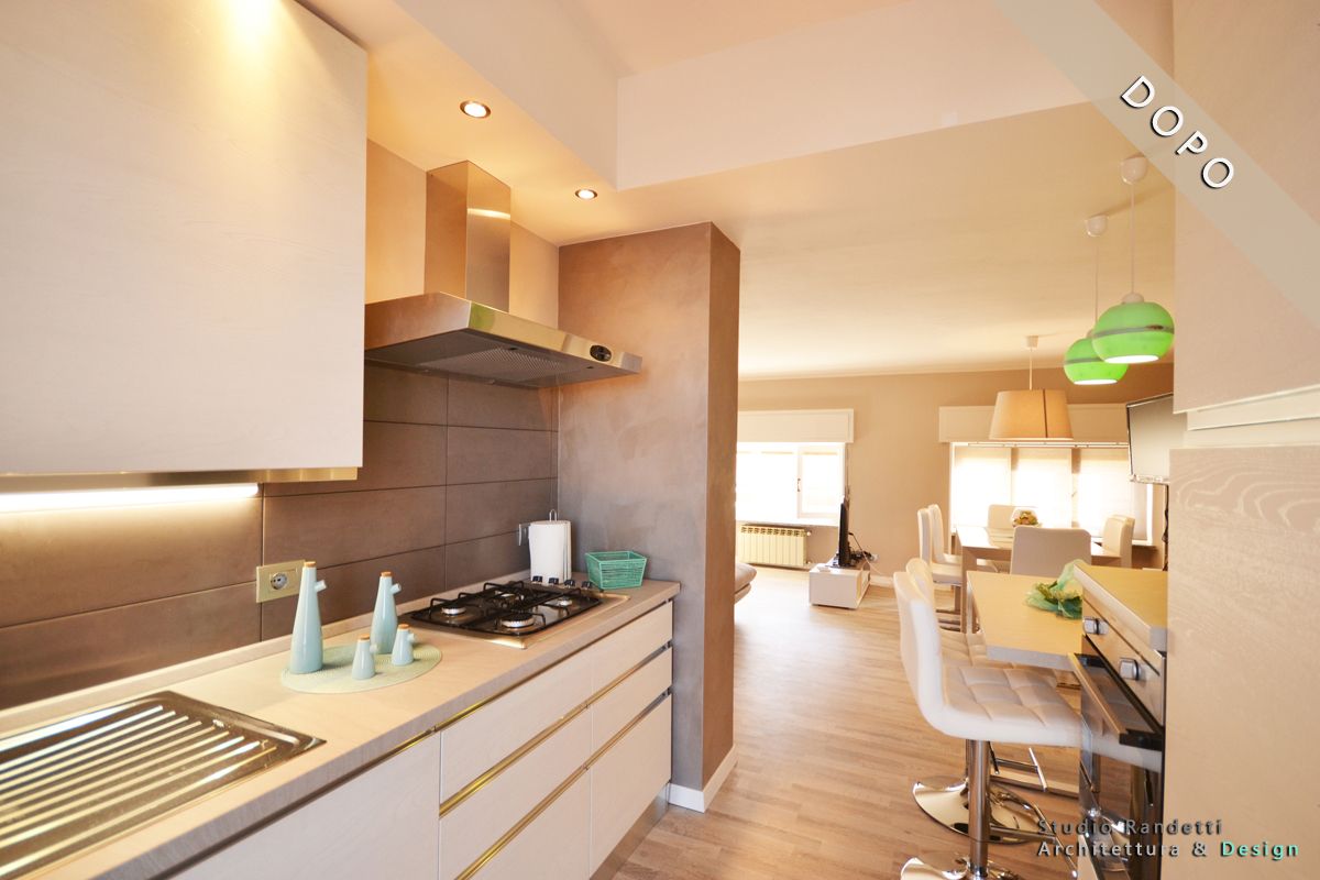 Cucina moderna e luminosa con mobili bianchi, pavimento in legno e vista sulla zona pranzo illuminata da lampade a sospensione verdi.