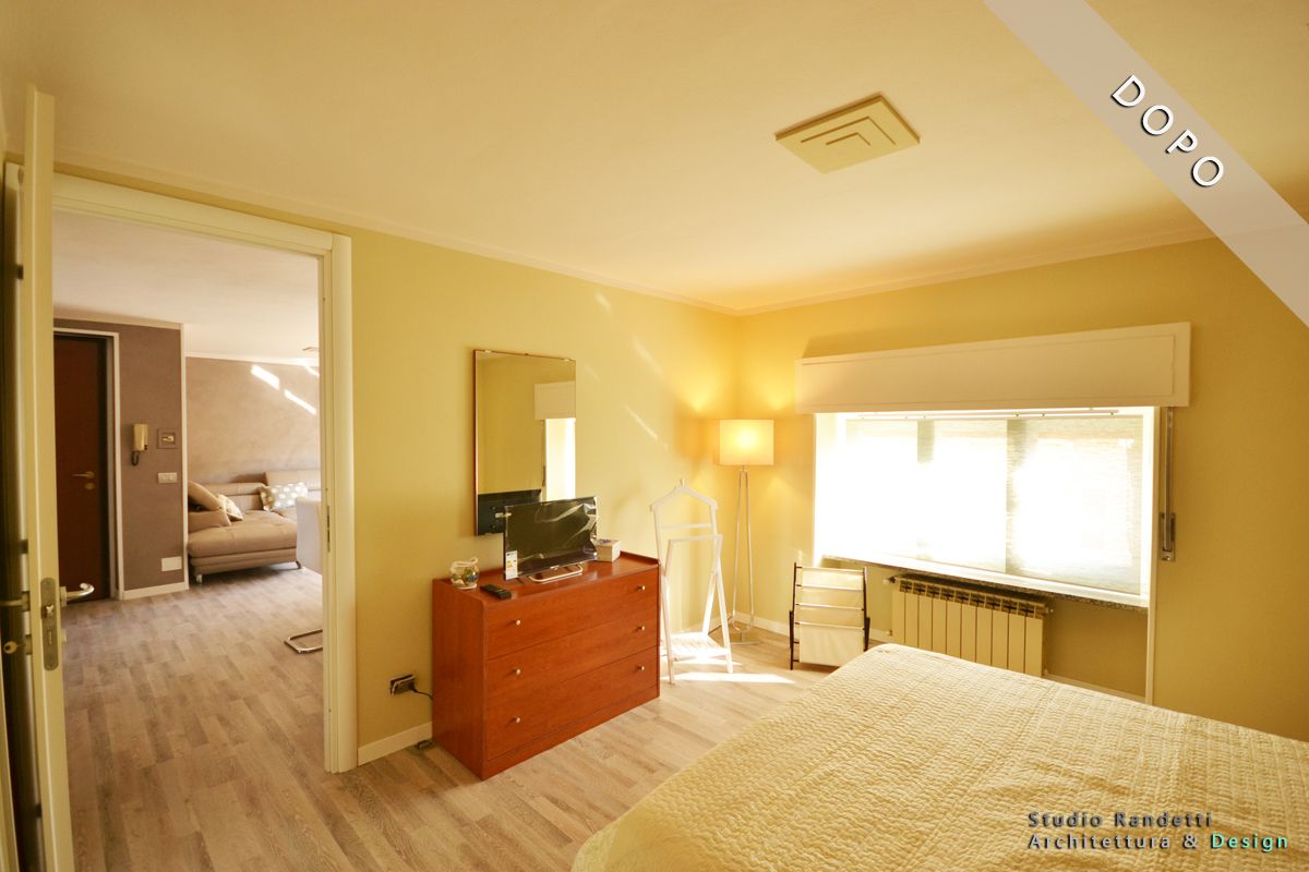 Camera da letto luminosa con letto, comò, lampada, TV e lucernario, vista dalla porta.