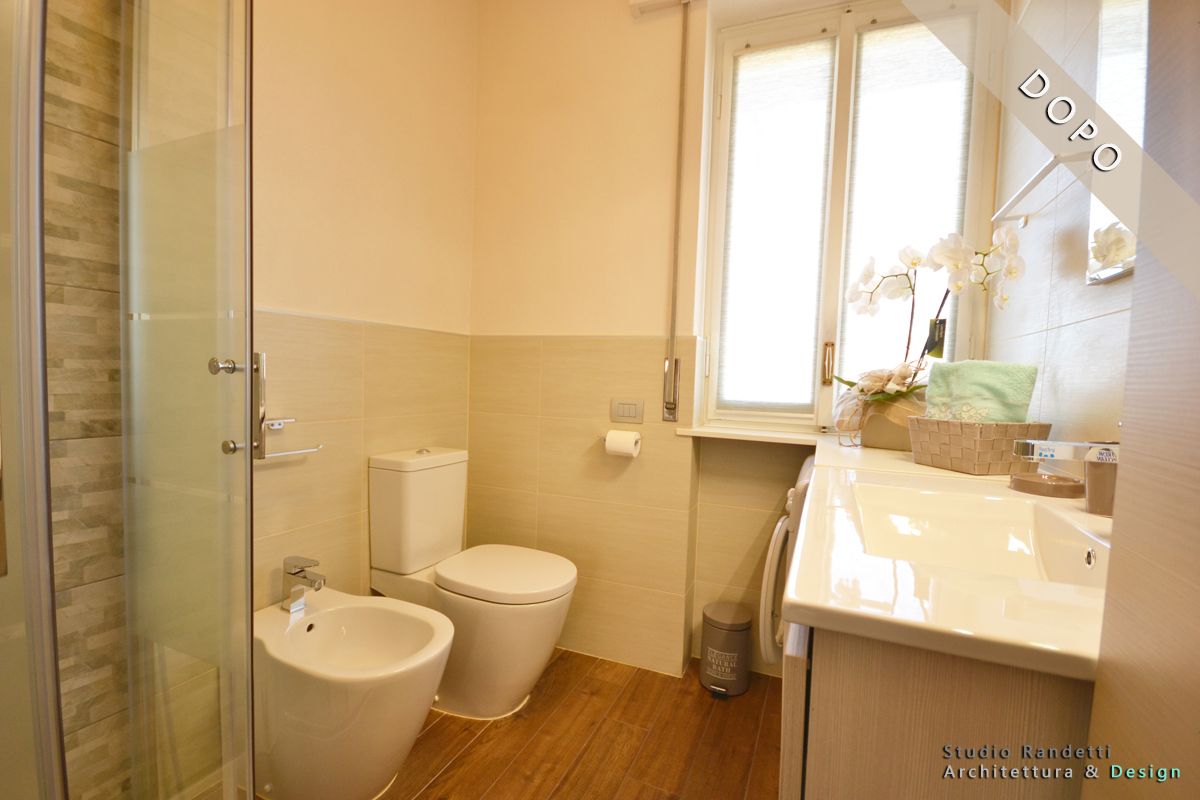 Luminoso bagno moderno con lavabo, WC, bidet, doccia e finestra sopra il mobiletto del bagno.