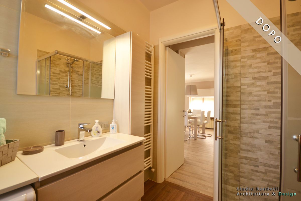 Bagno moderno con doppio lavabo, ampio specchio e porta aperta che conduce a una luminosa camera da letto.