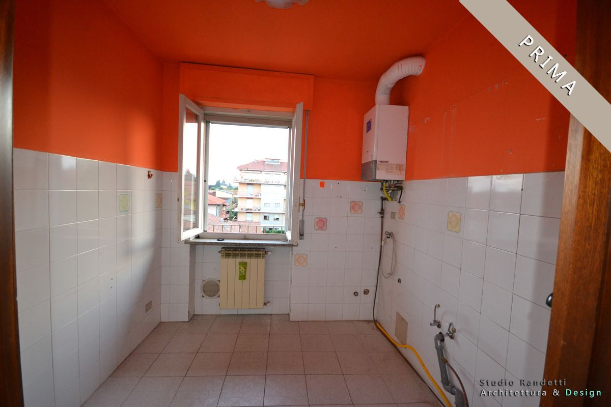 Piccola cucina con pareti arancioni, piastrelle bianche, una finestra e una caldaia a muro.