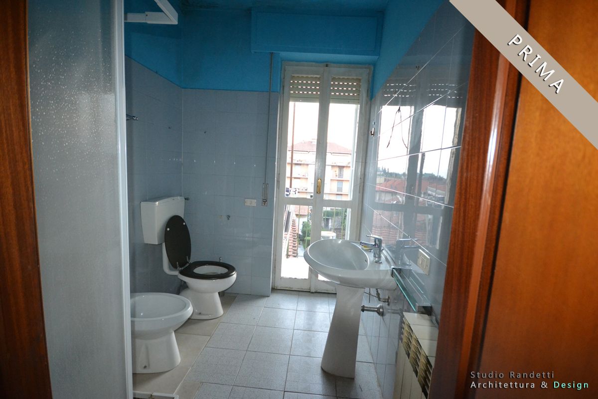 Bagno piastrellato di blu con WC, bidet, lavabo e zona doccia vicino a una finestra e una porta.