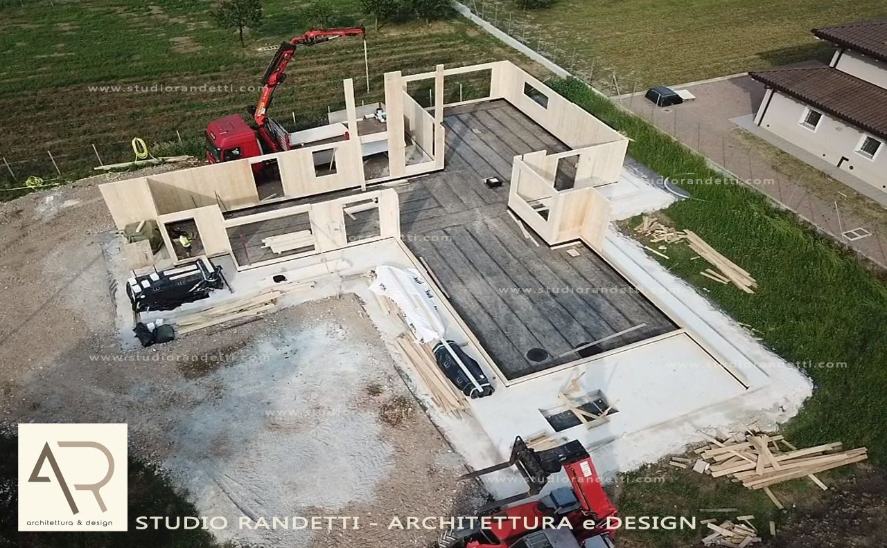 Veduta aerea delle fondamenta in cemento di una casa in costruzione, con un escavatore nelle vicinanze, in un campo rurale.