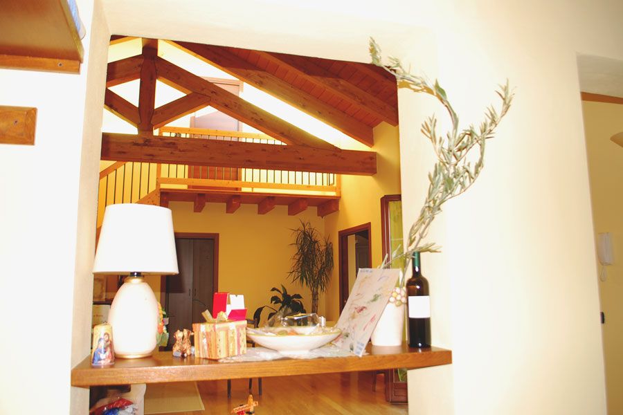 Tavolino decorativo con lampada e fiori in un corridoio luminoso, riflesso in uno specchio a parete