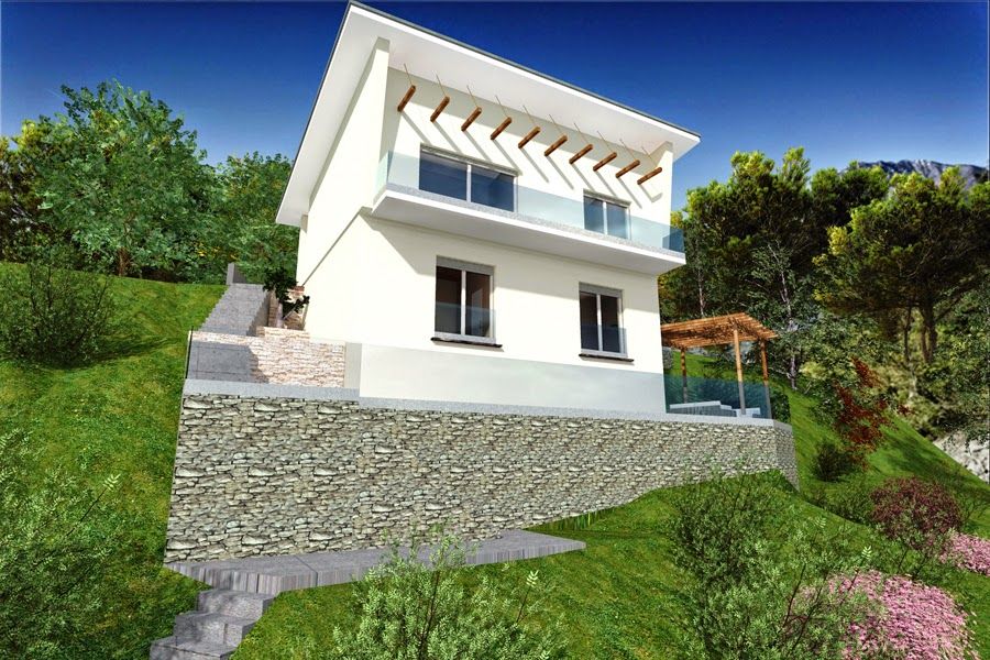 Casa moderna bianca su una collina con muro di contenimento in pietra, vegetazione e cielo azzurro.