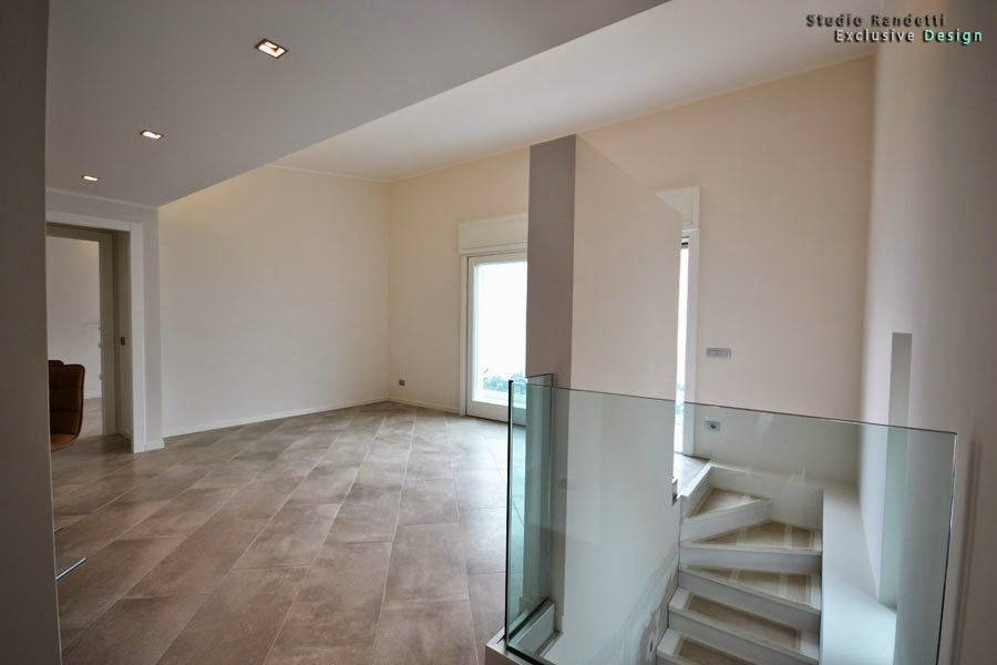 Interno moderno e vuoto con pavimento piastrellato, pareti bianche, ringhiera delle scale in vetro e faretti a incasso a soffitto.