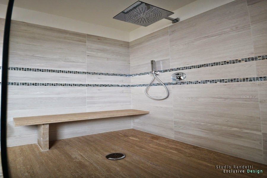 Bagno accessibile con doccia, doccetta a mano, maniglioni di sostegno e scarico a pavimento e pareti piastrellate.