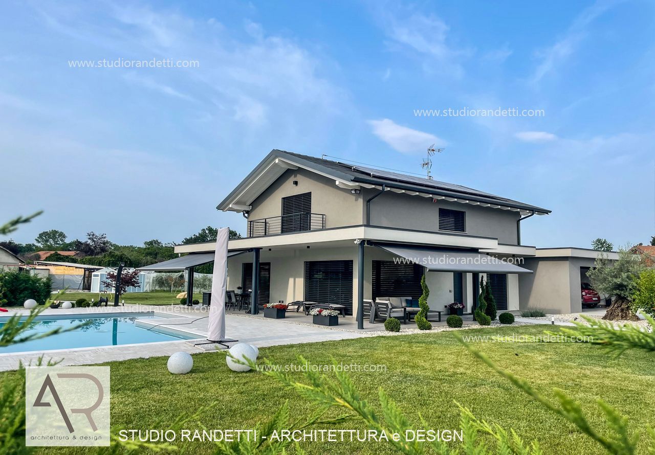 Casa moderna a due piani con piscina, prato e patio sotto un cielo azzurro
