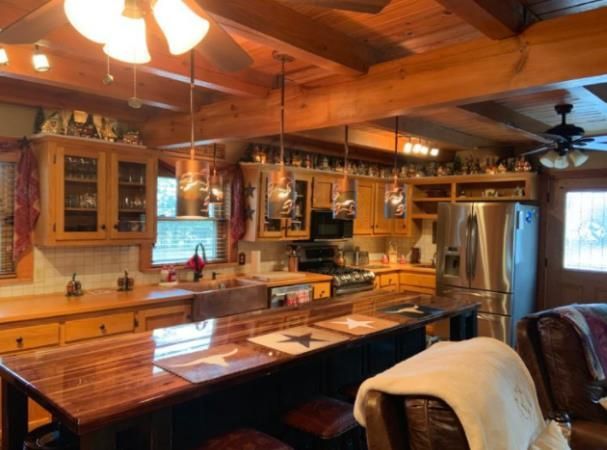 Rustic kitchen with wood cabinets, island, and stainless steel refrigerator.