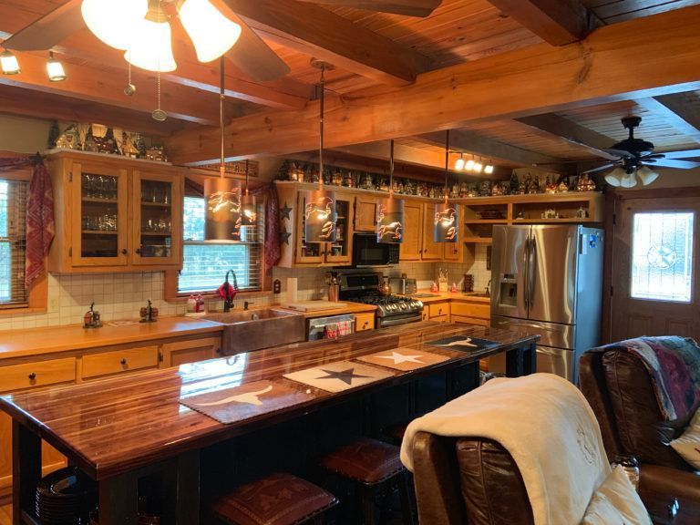 Rustic kitchen with wooden cabinets, island, and stainless steel appliances.
