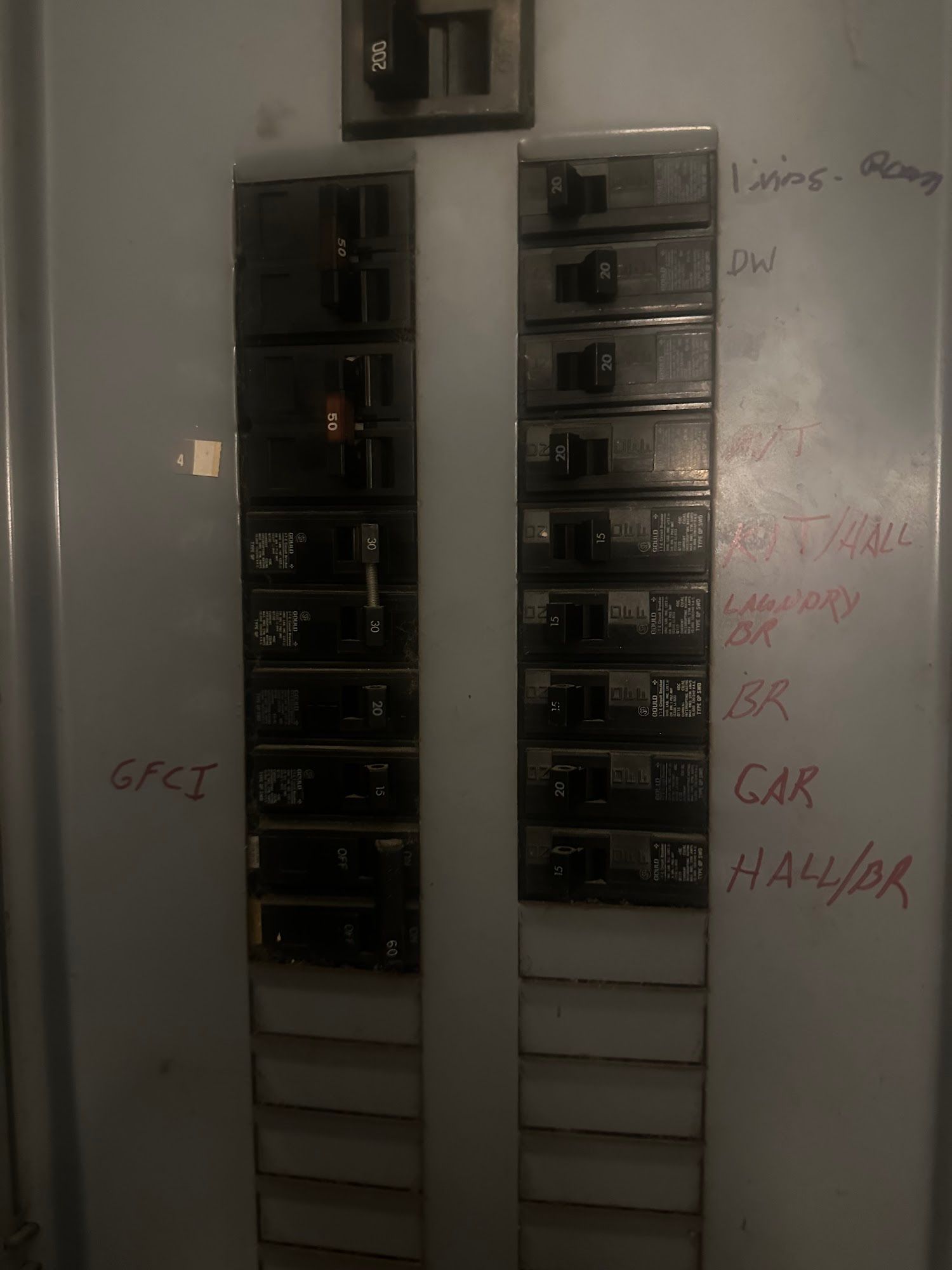 Electrical panel with numerous circuit breakers, some labeled with red marker.