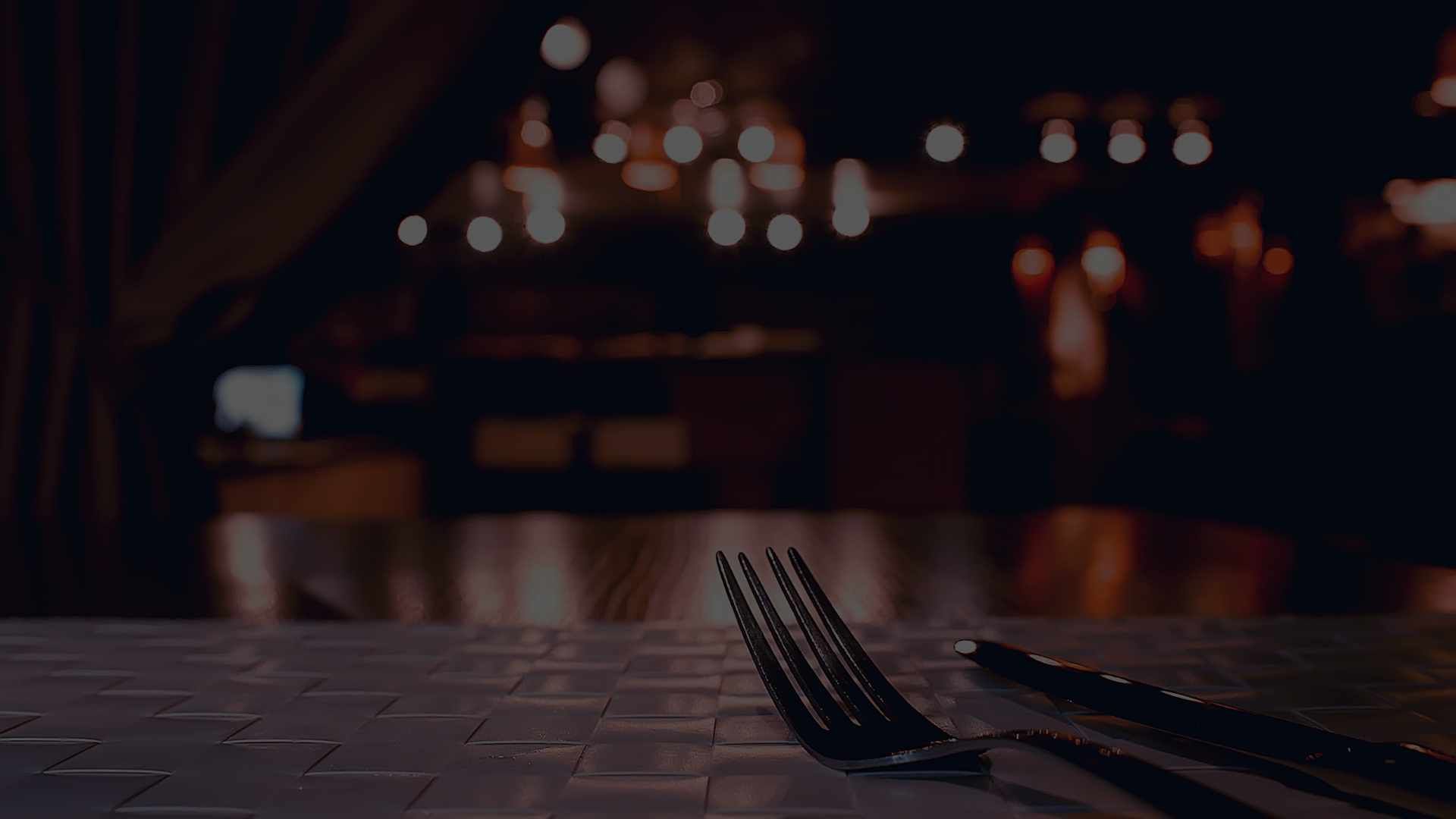 Very dark restaurant setting with cutlery on the table