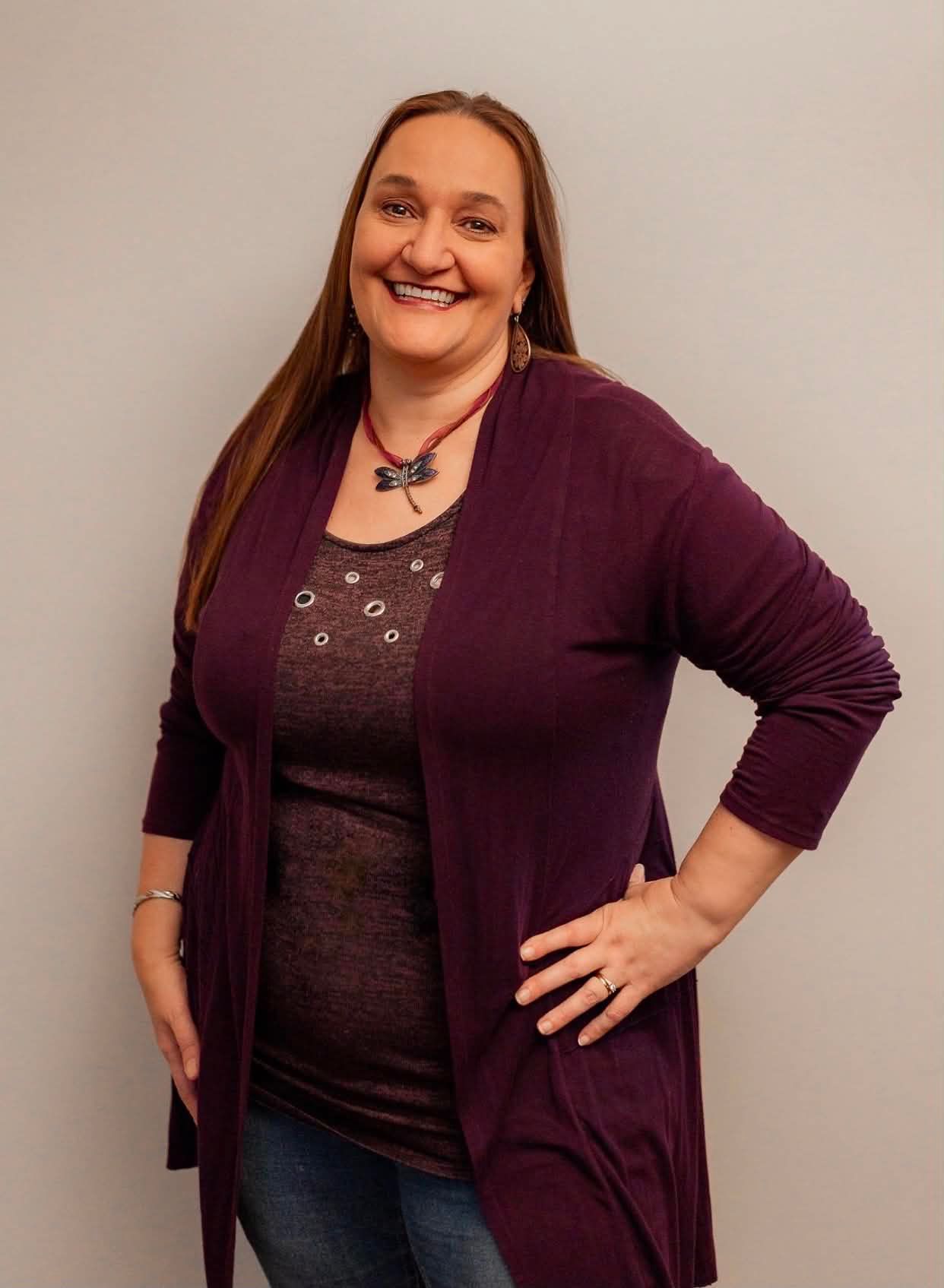 A portrait photo of Gina with a welcoming smile and a hand on her left hip.