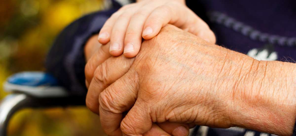 The hand of a small child on the hand of an elderly person in a show of affection