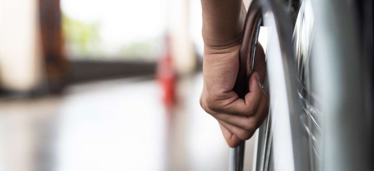 A person's hand on the handrim of a wheelchair.