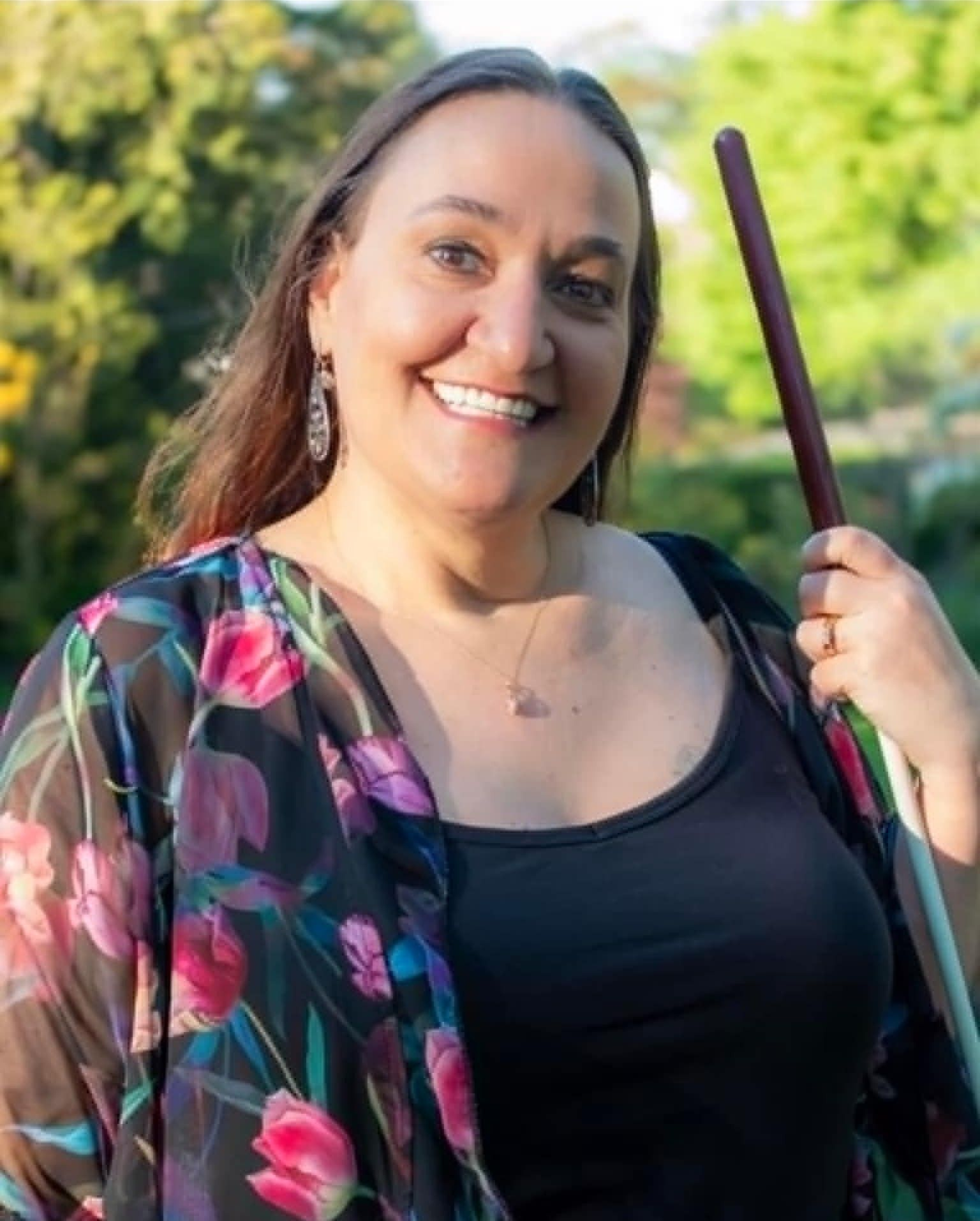 A portrait of Gina smiling and holding her cane.
